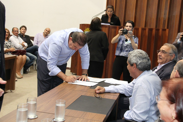 Na frente do presidente da Assembleia, deputado Jerson Domingos, e do governador André Puccinelli, Eduardo Rocha assina uma das 25 emendas que alcançaram 23 municípios (Foto: Divulgação)
