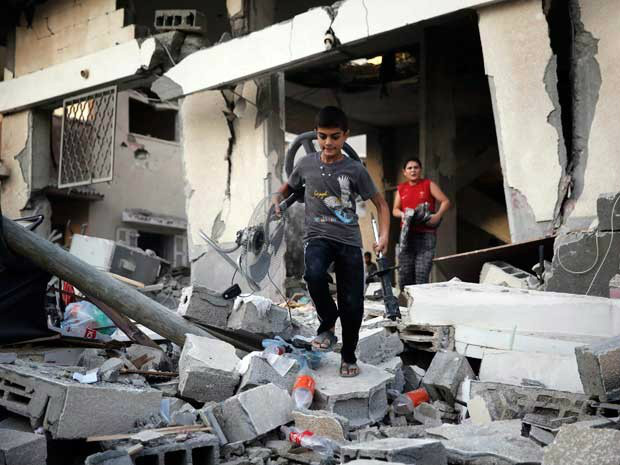 Meninos palestinos buscam pertences em uma casa danificada (Foto: Reuters/G1)