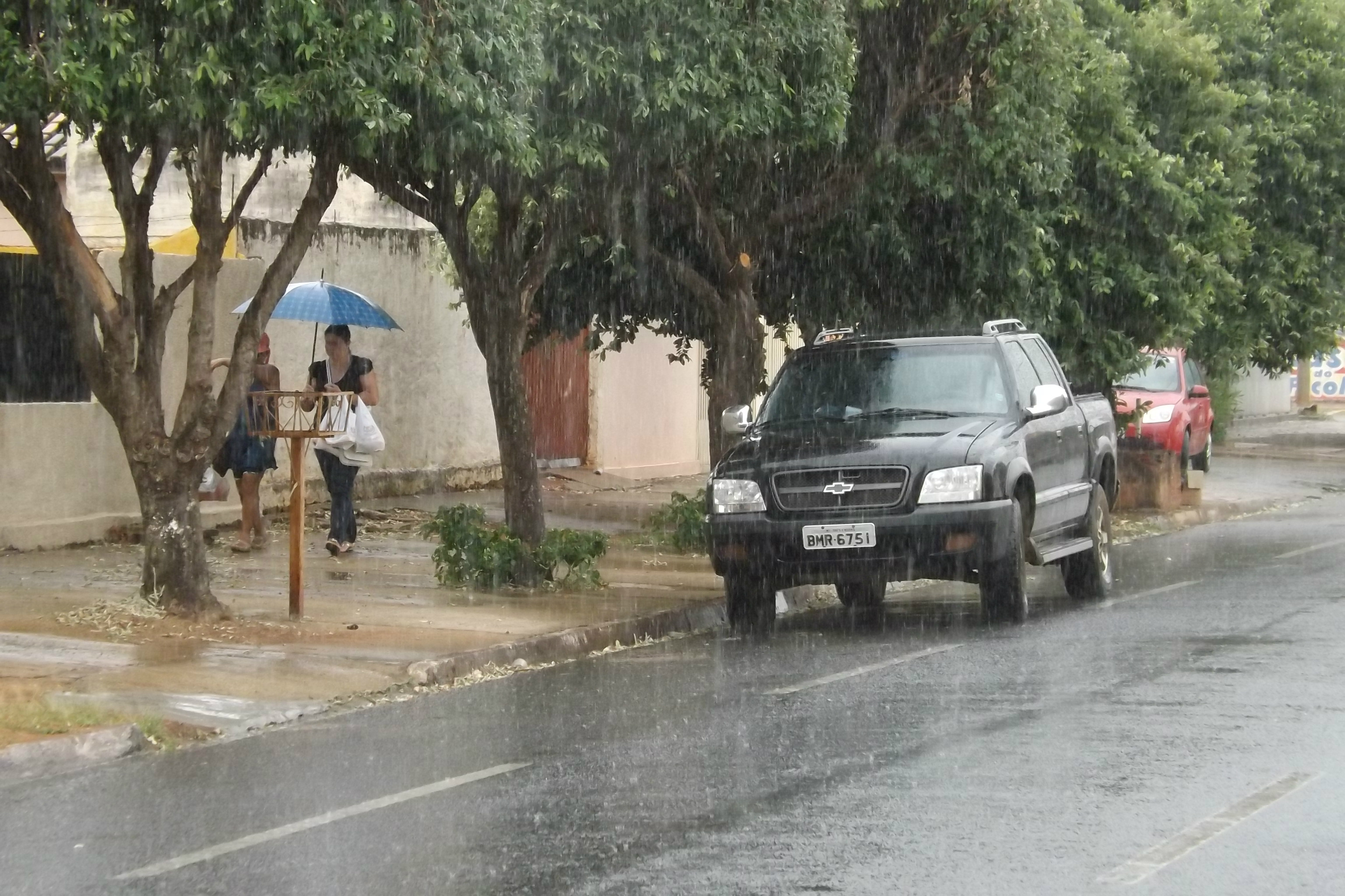 De volta das compras, as amigas disputam o guarda-chuvas que uma delas empunha para andar pela calçada, embaixo de fraca chuva, mas que pode molhar (Foto: Edivelton Kologi)