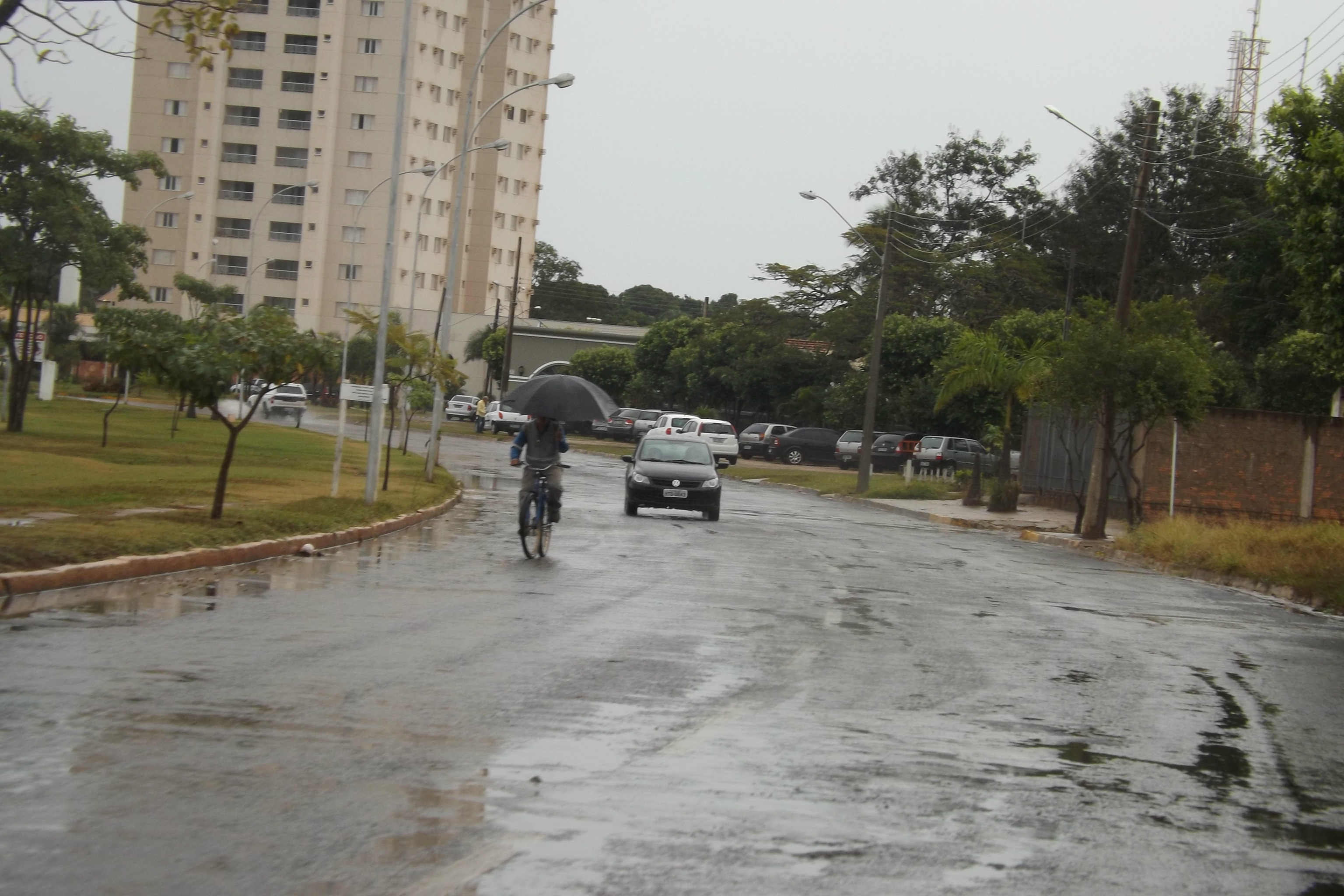 Avenida Aldair Rosa de Oliveira, a Circular da Lagoa: ciclista pedala enquanto se equilibra com um guarda-chuva (Foto: Edivelton Kologi)
