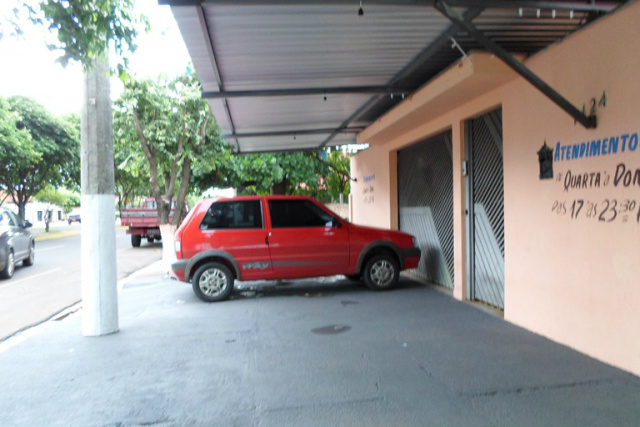 Um Fiat Uno estacionado na calçada em frente a garagem de uma casa, atrapalhando o trânsito de pedestres (Foto: Leo Lima)