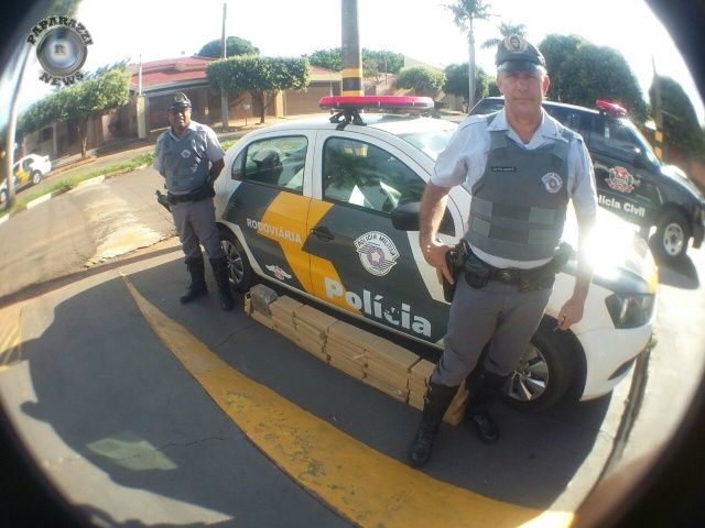 Os policiais que interceptaram o carregamento de drogas e os tabletes (no chão) de maconha (Foto: Paparazzi News)