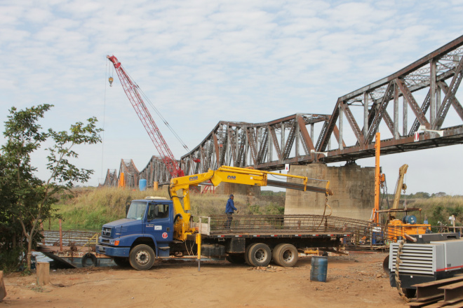 Equipamentos pesados foram transportados em balsa até o canteiro de obras: ao fundo bate estaca perfura o solo sub-aquático (Foto: Ricardo Ojeda) 