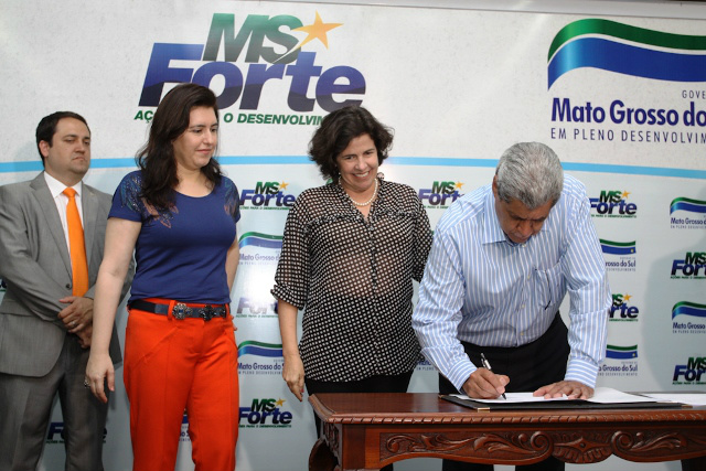 O governador assina documento autorizando o repasse de recursos para recuperação da avenida Filinto Muller, na presença de Simone e Marcia (Foto: Divulgação)