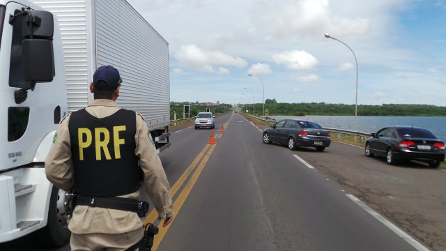Atento ao tráfego na rodovia, policial rodoviário federal se prepara para abordar 