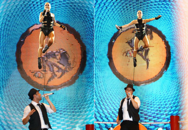 A cantora sendo suspensa no ar, por cabos de aço