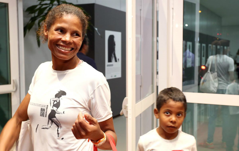 Parecia se esconder atrás das sacolas que segurava em um dos braços, enquanto o outro, segurava firme nas mãos do filho de 6 anos. (Foto: Divulgação)