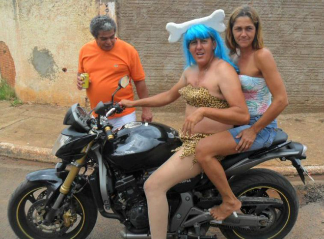 De moto e sem capacete, o folclórico líder comunitário e agora vereador Gil de Jupiá, travestida da personagem Pedrita, dos Flinstones (Foto extraída do Facebook)