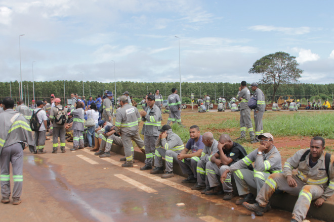 Trabalhadores que aderiram ao movimento de paralisação aguardam a chegada dos ônibus para transportá-los aos alojamentos (Foto: Ricardo Ojeda)