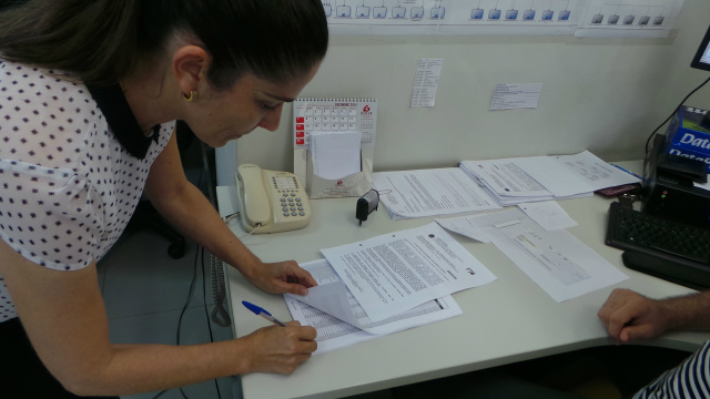 a magistrada Daniela Peruca assina as últimas planilhas com os nomes dos trabalhadores para enviar à Caixa Econômica Federal (Foto: Ricardo Ojeda)