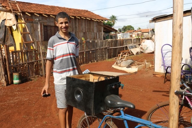 Menino cria sistema de energia para abastecer barracos após irmã morrer em incêndio causado por vela em MS Rogério e sua bicicleta que usa para anunciar propagandas de empresas de Sidrolândia (MS). — Foto: Site Região News