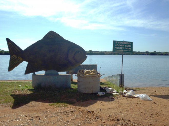 Garrafas PET e latas de milho verde engrossam lixo no rio No pé da escultura de peixe, placa adverte para não jogar lixo, mas tambor tem até cobertor velho. (Foto: Edmir Conceição)