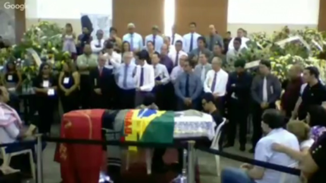 Pastores prestam às últimas homenagens à Marcos Rogério Cerimônia de corpo presente está sendo realizado nesse mimento e em seguida sairá em cortejo no caminhão do Corpo de Bombeiros até o cemitério municipal (Foto: Reprodução You Tube)