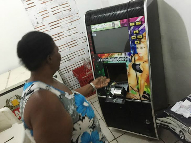 Ladrão arromba porta de bar, furta moedas de jukebox e ainda leva bebidas Nalva mostra a máquina de música, de onde o ladrão conseguiu