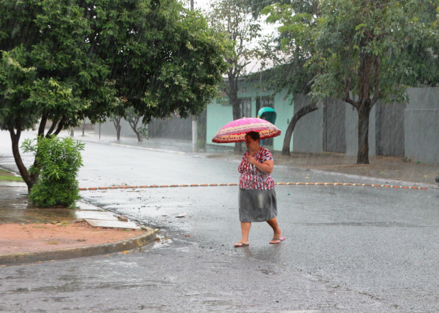 Moradora usa um guarda-chuva para se proteger. (Foto: Lucas Gustavo).