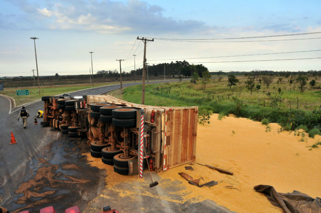 Carreta carregada de milho tomba em rotatória na BR Carga de milho foi removida da pista por equipe do Corpo de Bombeiros (Foto: Valdenir Rezende / Correio do Estado)