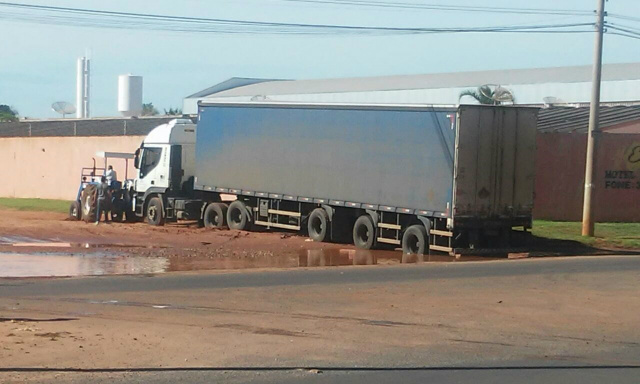 Ao desviar da poça d'água carreta fica atolada na rua Baldomero Leituga e trator teve que ser acionado (Foto: Djair Martinez) 