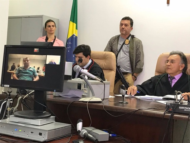 No monitor, Cesare Battisti, e à direita, o juiz federal Odilon de Oliveira durante audiência de custódia por videoconferência na Justiça Federal em MS (Foto: Claudia Gaigher/TV Morena)