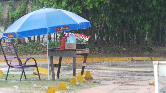 A chuva não impediu que o ambulante improvisasse uma barraquinha para poder faturar na venda de velas e flores. (Foto: Ricardo Ojeda)