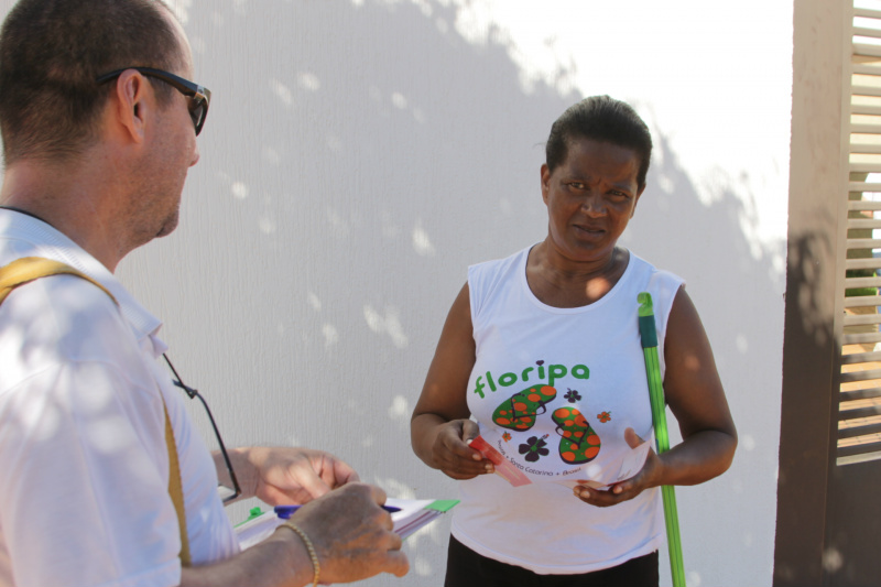 Dona Amélia dá um tempo na varrição da calçada para atender o agente da saúde (Foto: Léo Lima)