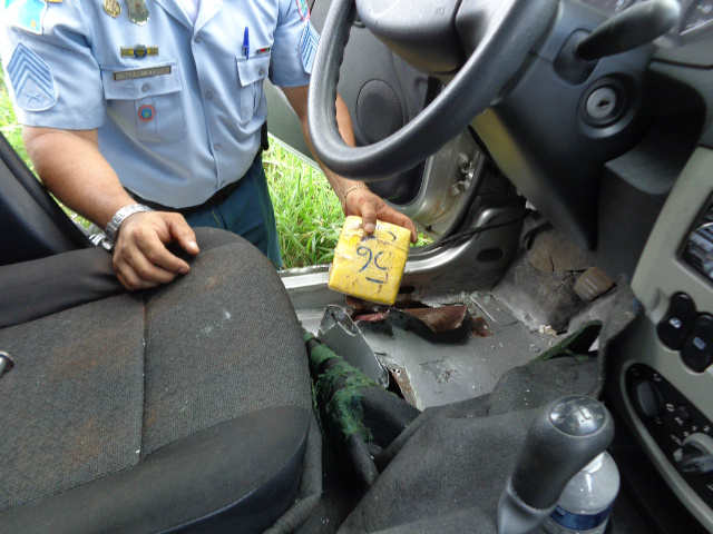 Policial mostra onde estavam escondidos os tabletes com os mais de 52 quilos de pasta base (Foto: Divulgação)