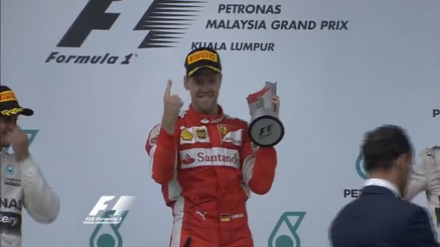 Vettel vence Grande Prêmio da Malásia; Massa chega em sexto lugar Sob olhar decepcionado de Hamilton (esquerda), Vettel aponta com o indicador sua posição na chegada, com a taça na mão (Foto: Reprodução/Rede Globo))