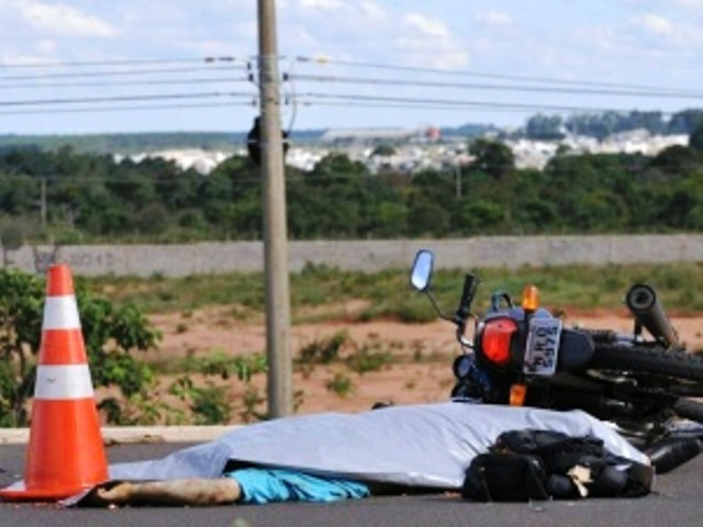 Corpo da vítima foi coberto até a chegada da perícia técnica; ao lado a moto que pilotava (Foto: CG News)