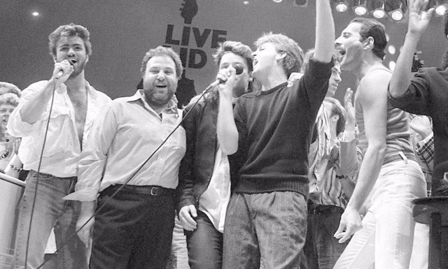 Hoje é o Dia Mundial do Rock! Você sabe por quê? George Michael, Harvey Goldsmith, Bono, Paul McCartney, Bob Geldof e Freddie Mercury no Live Aid, em Wembley, em 1985 (JOE SCHABER / ASSOCIATED PRESS)