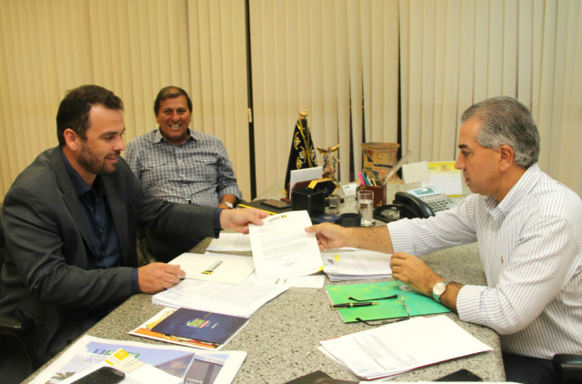 O presidente da Assomasul (Associação dos Municípios de Mato Grosso do Sul), Juvenal Neto entrega a proposta para o governador Reinaldo Azambuja. (Foto: Assessoria)