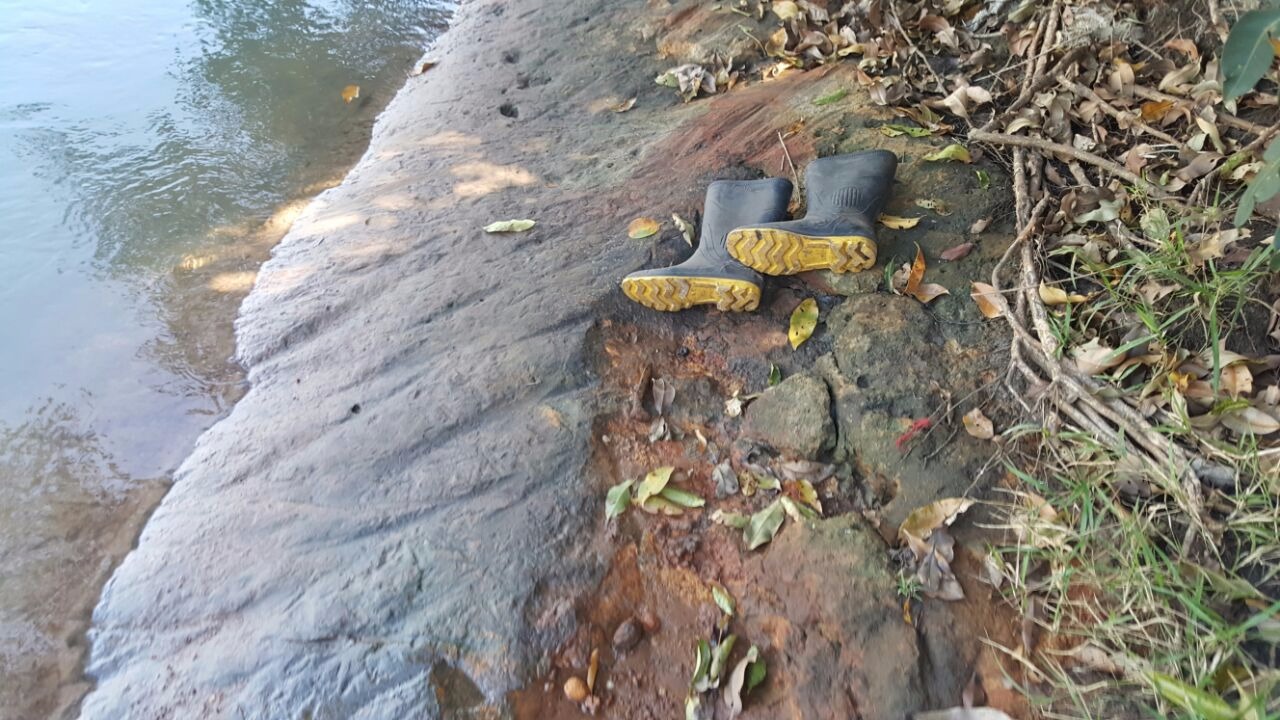 Par de botas deixados pelo jovem na beira do rio e encontrado por seus tios. (Foto: Divulgação/ Corpo de Bombeiros). 