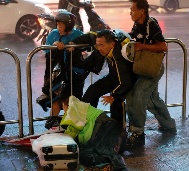 Pessoas se seguram para ficar em pé durante a passagem de tufão em Taipé, Taiwan, neste domingo (30) (Foto: Tyrone Siu/Reuters)