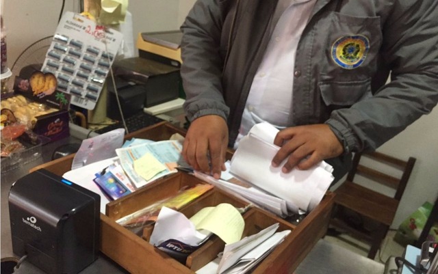 Servidor da CGU analisa documentos em lojas de Paranhos (MS) (Foto: PF/Divulgação)