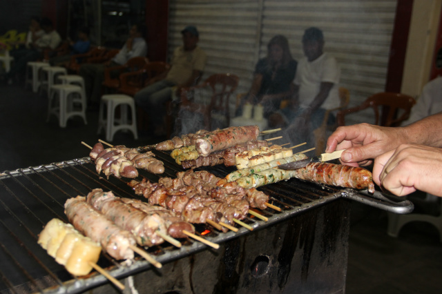 Em uma churrasqueira antiga, com brasas atiçadas por um velho ventilador, Cacau atende uma clientela cativa que não reclama em esperar na calçada o espetinho  (Foto: Polllyana Elloy)  