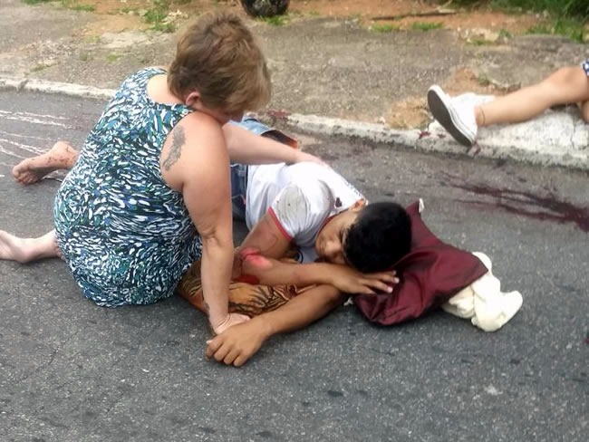 Rapaz tem perna amputada ao empinar moto Rapaz recebendo a ajuda de moradores antes da chegada do Samu. (Foto: Divulgação).