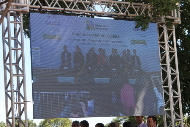 Em telões espalhados pelo local, houve a transmissão simultânea da entrega das unidades habitacionais, no qual a presidente Dilma Rousseff participou, junto com ministros. (Foto: Patrícia Miranda)