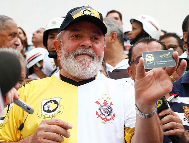 Com uma camisa metade São Bernardo e metade Corinthians, o ex-presidente Lula exibe sua carteirinha de sócio-torcedor do 